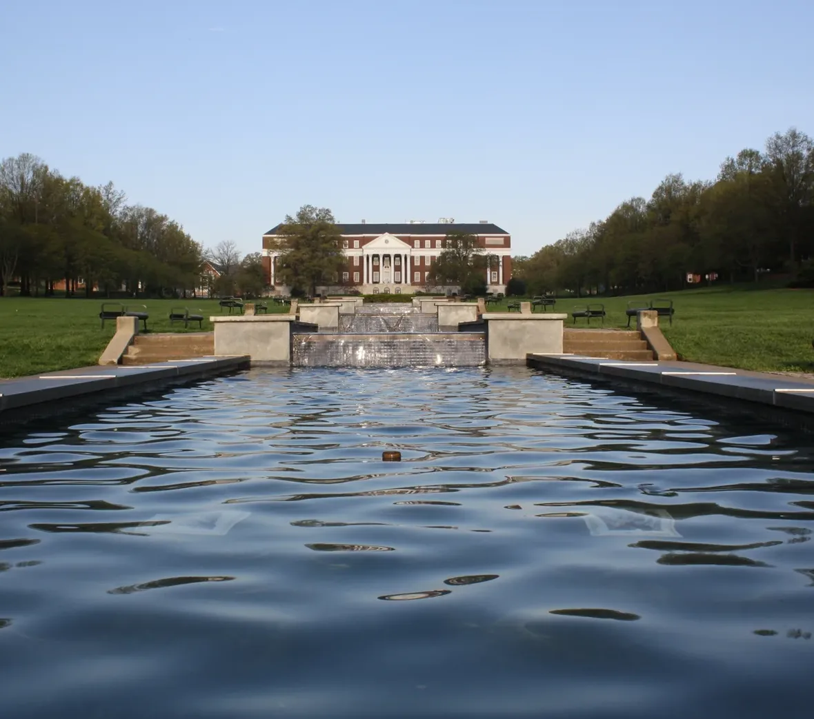 The McKeldin Mall reflecting pool leads to a columned library under a clear sky