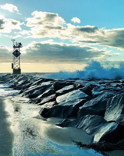 Spray over a jetty beside a lighthouse