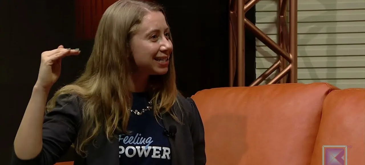 A guest in an MPOWER shirt talks on a studio sofa during a Nepali TV interview