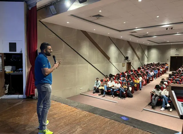 A speaker with a microphone addresses a packed lecture hall